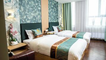 Habitación de hotel con dos camas, una mesita de noche, una lámpara y un ventanal con cortinas.