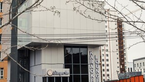 Een modern gebouw met een bord waarop 'Karaoke Lounge' en 'Sing-a-la' staat.