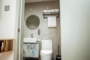 A modern bathroom with a marble sink, a toilet, a mirror, and a towel rack with branded towels. - Singala Hotel Ulaanbaatar (Ulaanbaatar)