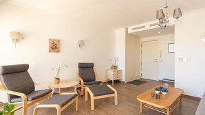 Ett modernt vardagsrum med en soffa, två fåtöljer, ett soffbord och ett litet sidobord med en lampa och en växt.