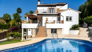 Una casa de dos pisos con piscina, un balcón y una escalera que sube al piso superior.