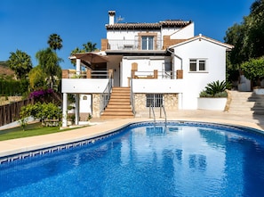 Ein zweistöckiges Haus mit Swimmingpool, einem Balkon und einer Treppe, die zu der oberen Etage führt.