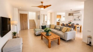 Una sala de estar moderna con sofá, mesa de centro y televisor.