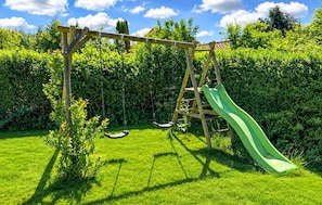 A wooden swing set with a green slide in a lush green garden. - 3 bedroom amazing home in Nordborg (Nordborg)
