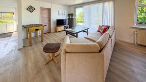 Ein Wohnzimmer mit einer Couch, einem Couchtisch, einem Fernseher und einem Kicker.