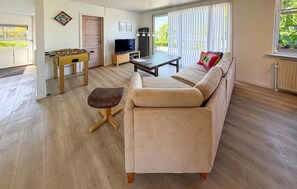 A living room with a sofa, a coffee table, a television, and a foosball table. - 3 bedroom amazing home in Nordborg (Nordborg)