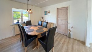 Ein Essbereich mit einem runden Holztisch, schwarzen Stühlen und einer Hängelampe.