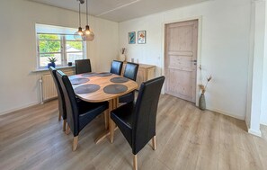 A dining area with a round wooden table, black chairs, and a hanging light fixture. - 3 bedroom amazing home in Nordborg (Nordborg)