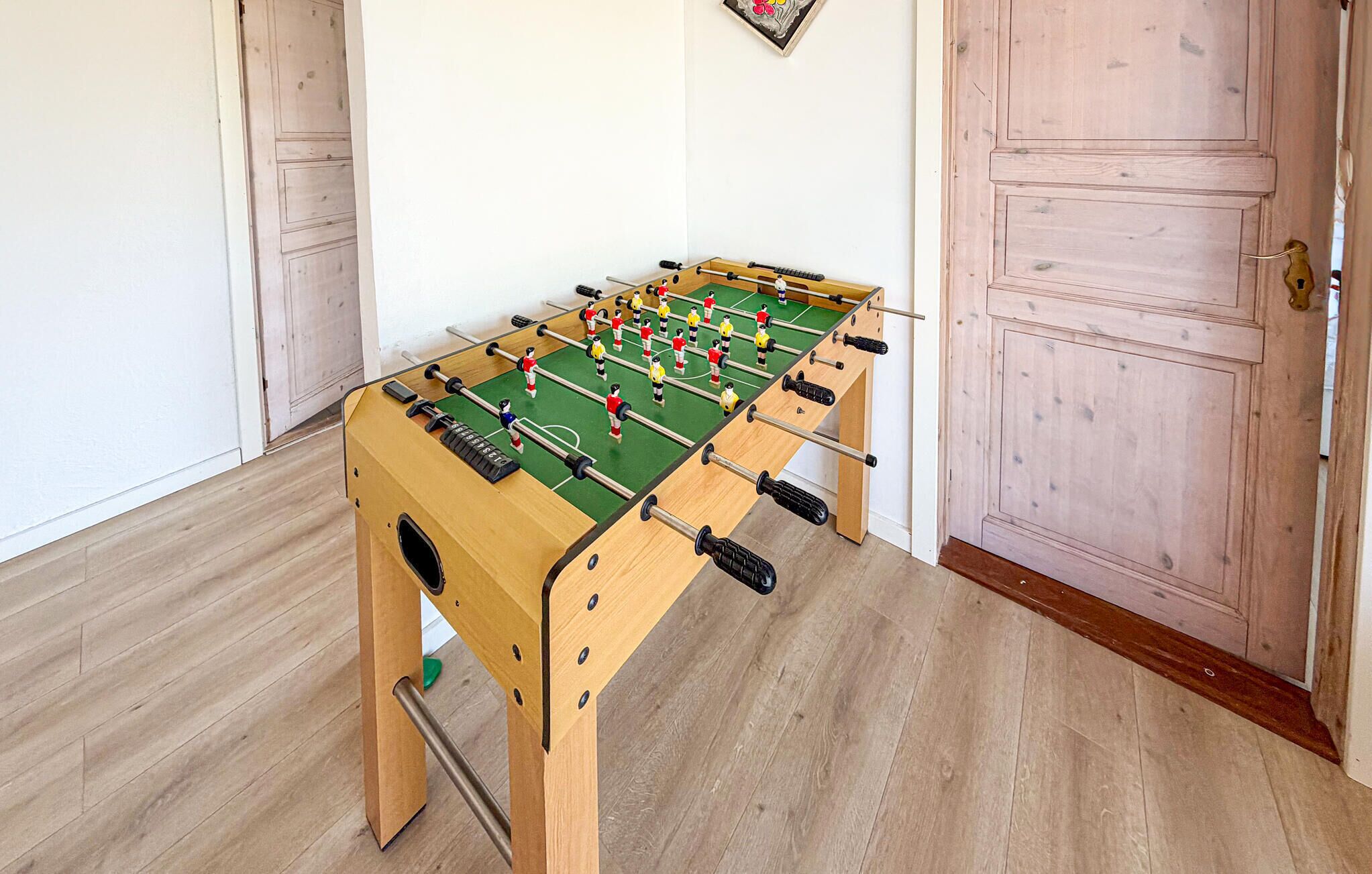 Un tavolo da calcio in legno in una stanza con pavimento e porta in legno.