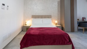Une chambre à coucher moderne avec un lit, des lampes de chevet, un bureau et une chaise.