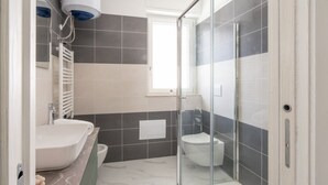 Une salle de bain avec douche, toilettes et lavabo.