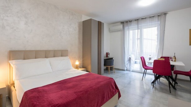 Une chambre d’hôtel avec un lit, un bureau, une chaise et une fenêtre.