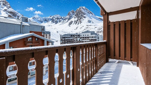 Un balcone con vista sulle montagne innevate e sugli edifici.