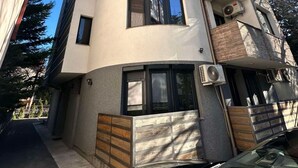 Een modern gebouw met een gebogen gevel, grote ramen en een balkon met houten leuning.