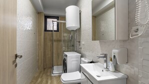 Een kleine badkamer met douche, toilet en wastafel, met een betegelde muur en een houten vloer.