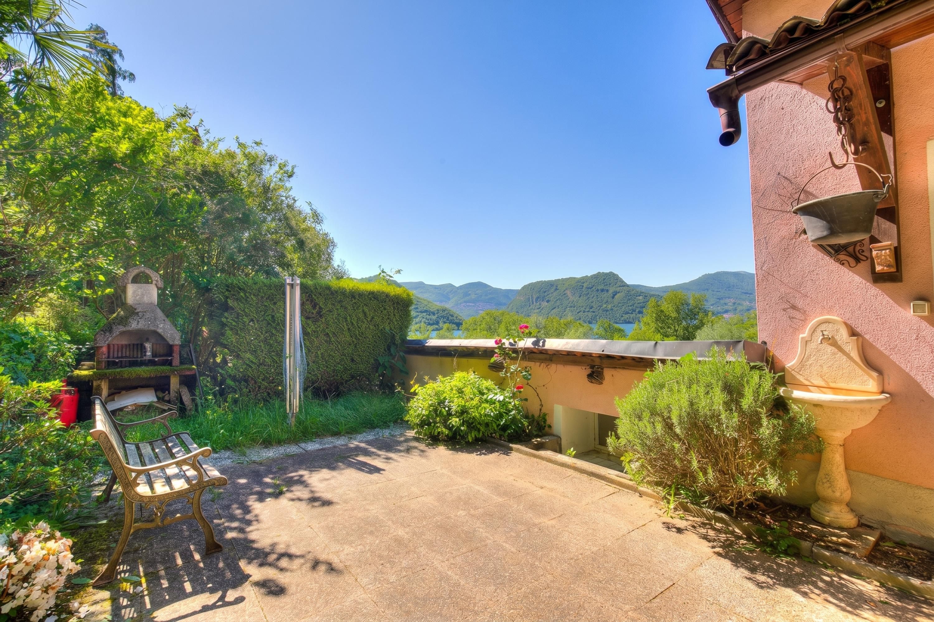 Un patio con una panchina, una struttura in pietra e vista sulle montagne.