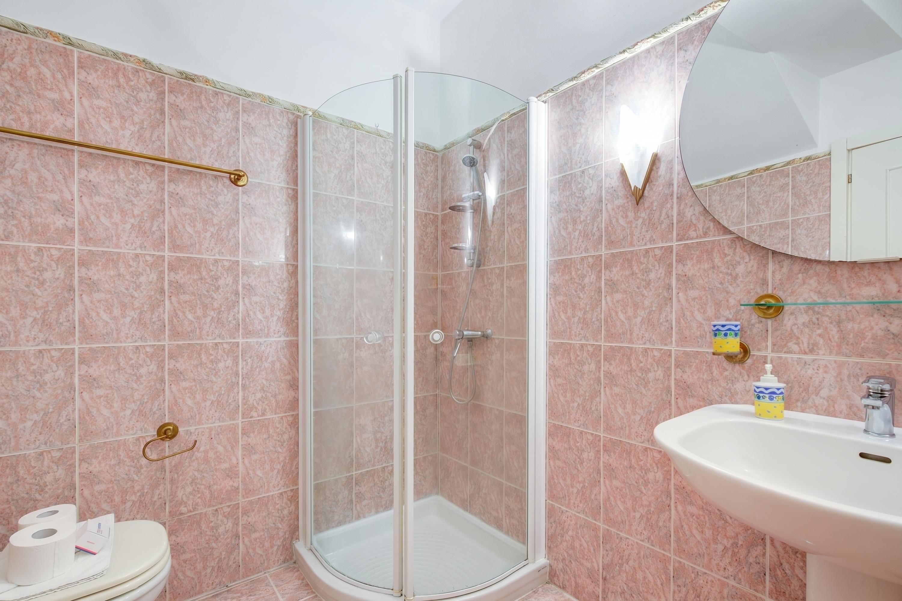 Une salle de bain avec une douche à parois de verre, un lavabo blanc et des toilettes.