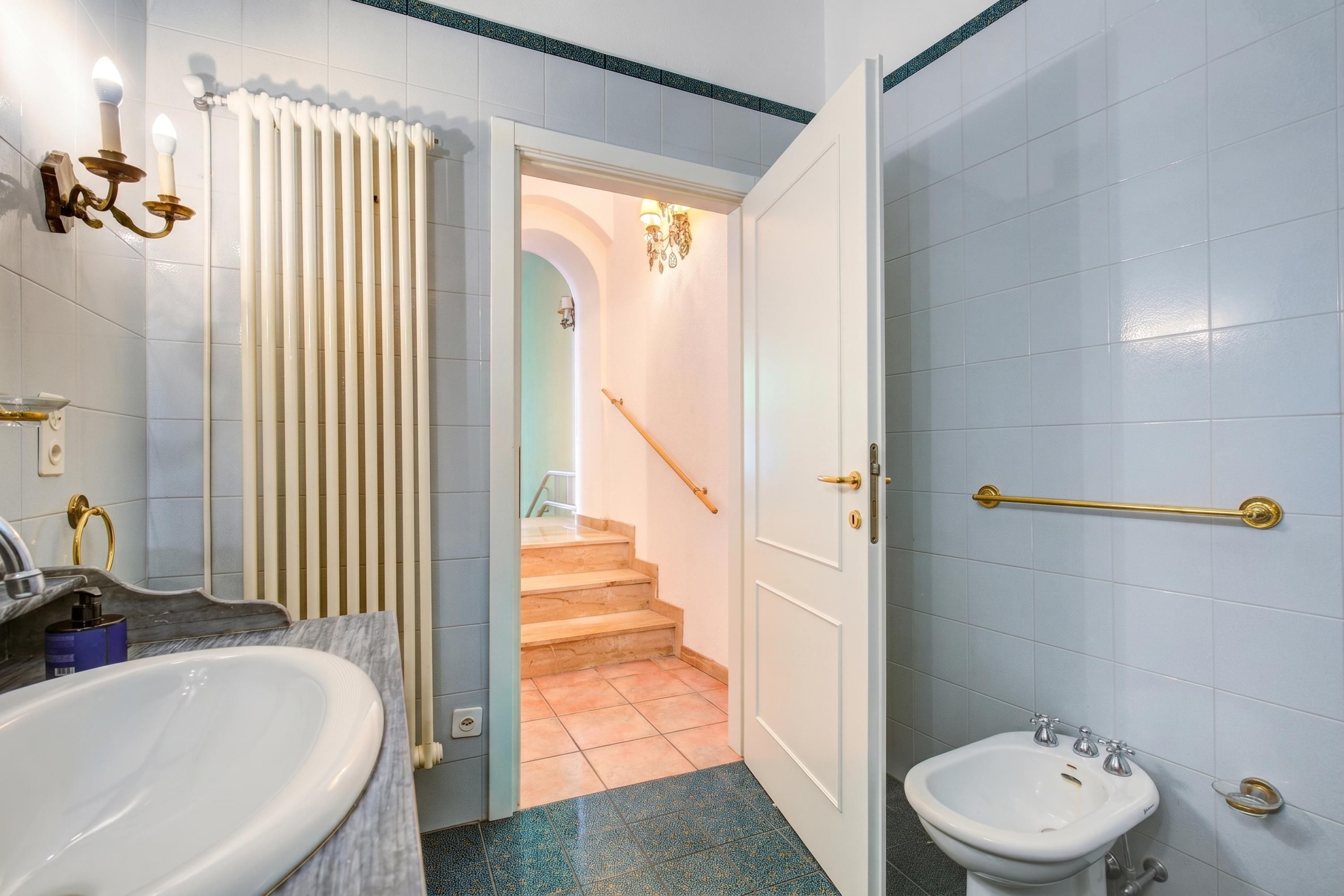 A bathroom with a large sink, a smaller basin, a towel rack, and a handrail.