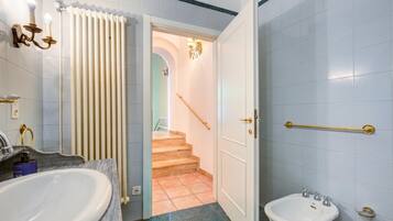 A bathroom with a large sink, a smaller basin, a towel rack, and a handrail.