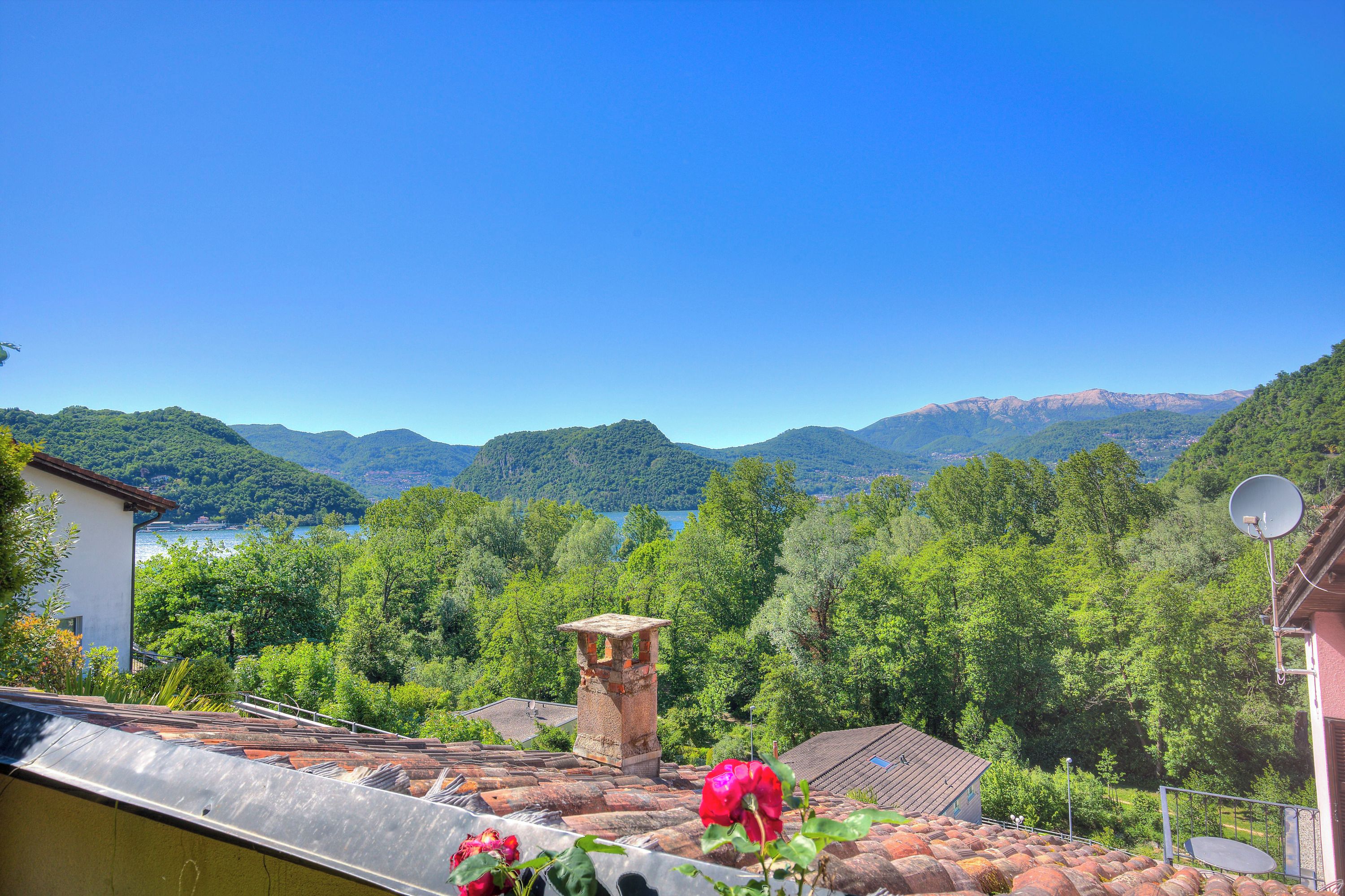 A view of a mountainous landscape with a clear sky, a body of water, and lush greenery.