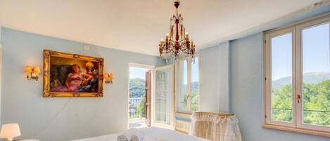 Una camera da letto con un letto, un lampadario, un quadro e vista dalla finestra.