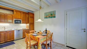 Una cocina con armarios de madera, microondas y una mesa de comedor preparada para cuatro personas con sillas.