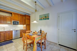 Una cocina con armarios de madera, microondas y una mesa de comedor preparada para cuatro personas con sillas.