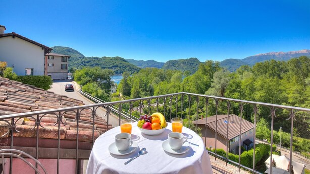 Un balcon avec une table préparée pour le petit-déjeuner, offrant une vue sur un paysage montagneux.