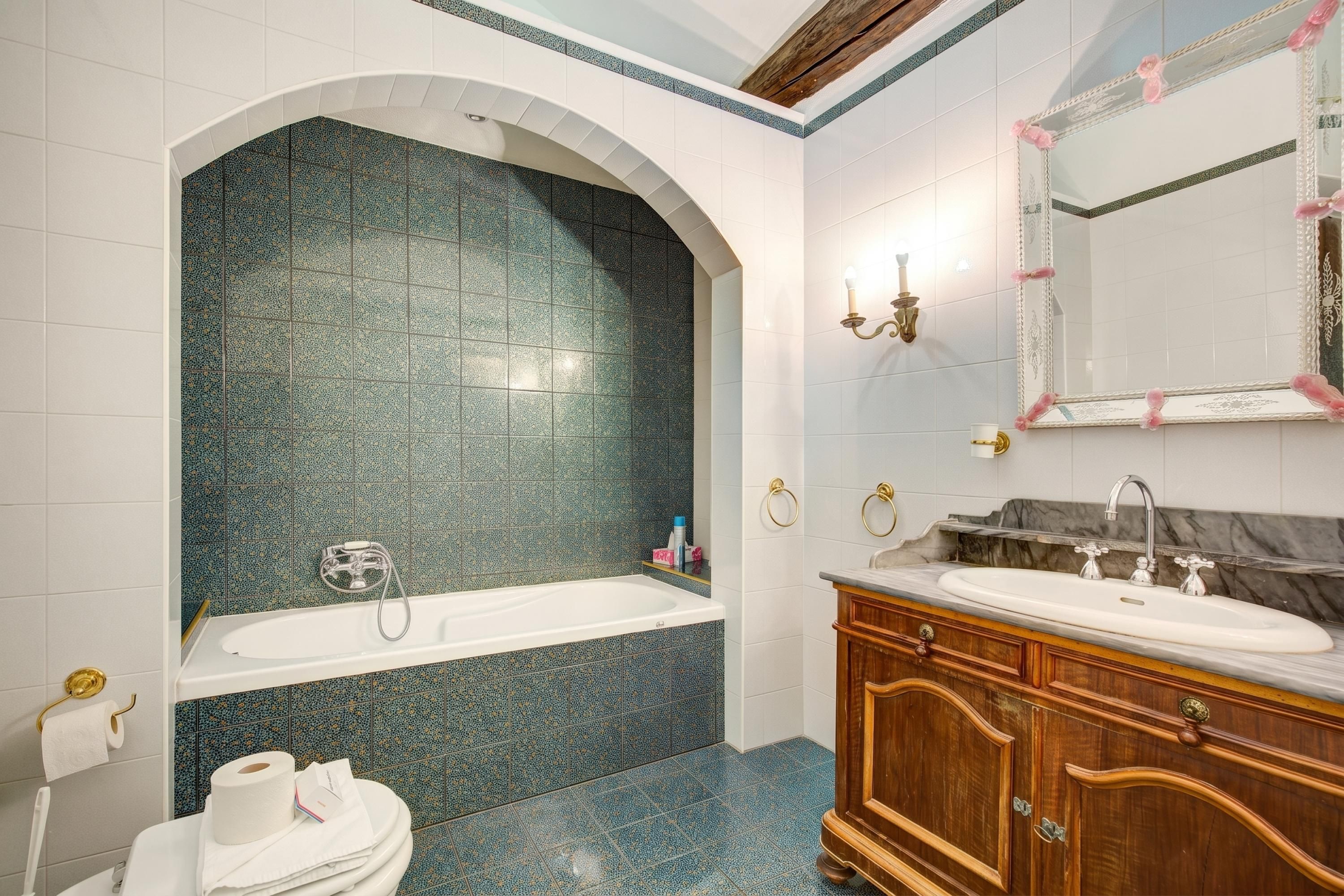 A bathroom with a bathtub, a vanity with a sink, and a mirror.