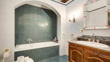 A bathroom with a bathtub, a vanity with a sink, and a mirror.