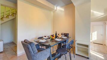 A dining area with a glass table, chairs, and a fruit bowl.