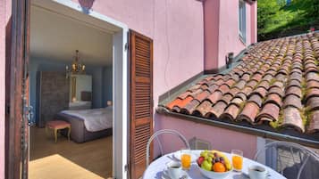 Une chambre avec un lit, une table où le petit-déjeuner est servi, et une vue sur l’extérieur.