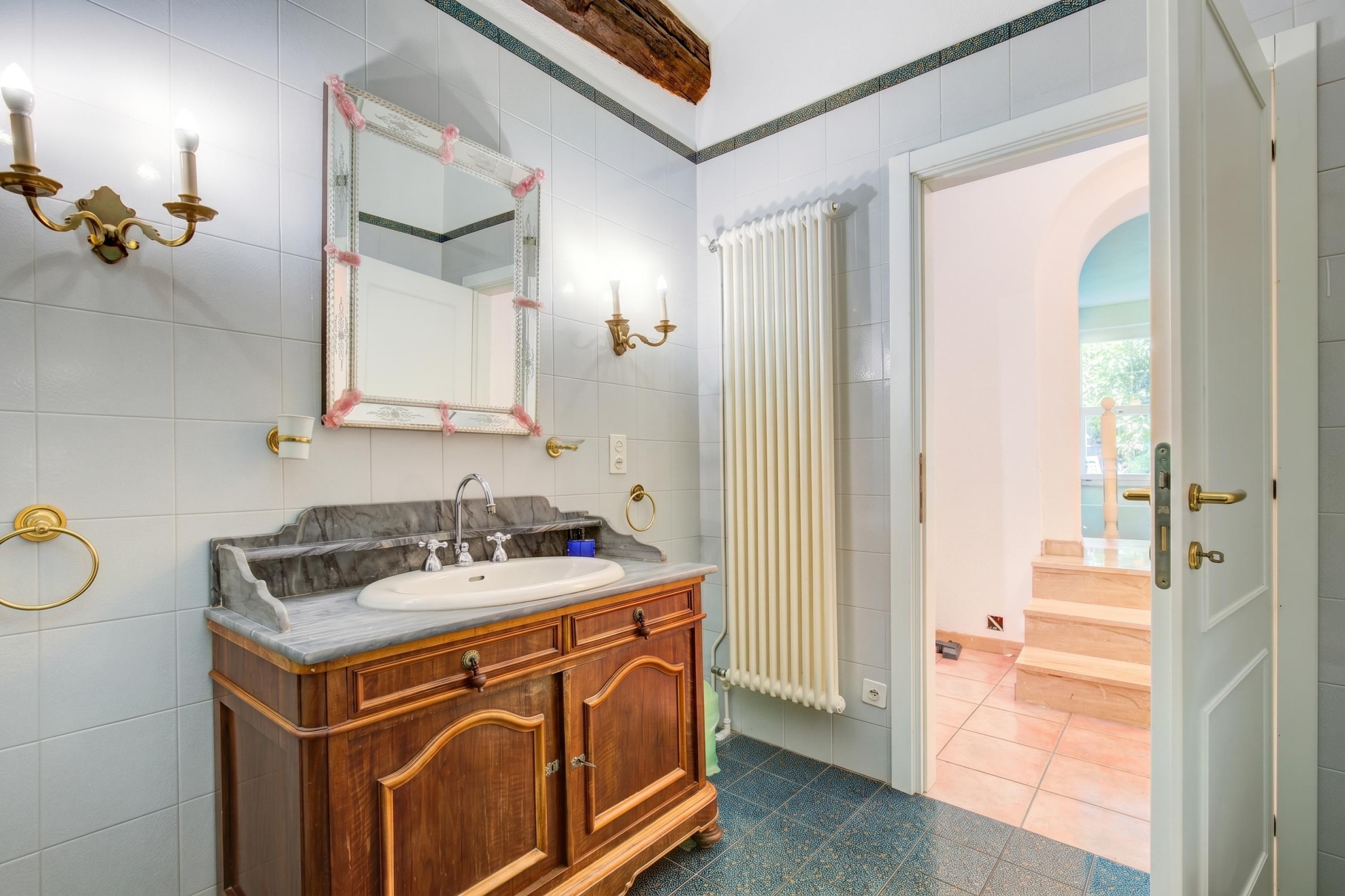 Un bagno con un lavabo in marmo, un mobile vanitario in legno e un ampio specchio.