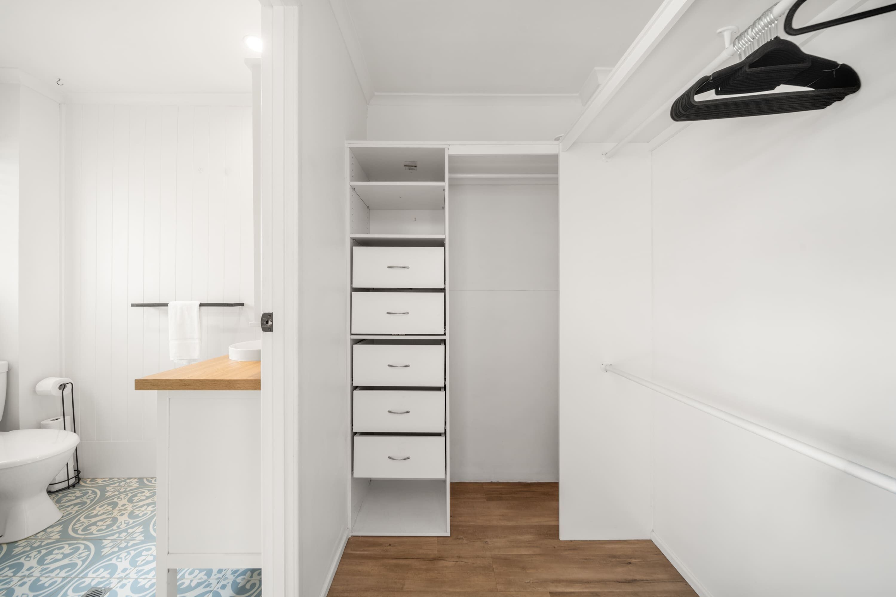 Un armadio bianco con diversi cassetti e uno scaffale in legno.