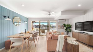 Una sala de estar moderna con comedor, un sofá, televisor y un ventanal con vistas.