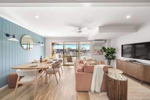 Ein modernes Wohnzimmer mit Essbereich, einer Couch, einem Fernseher und einem großen Fenster mit Blick.