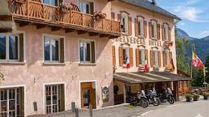 A hotel with balconies, a sign reading 'BELVEDERE HOTEL', flags, and motorcycles parked outside. - Hôtel Le Belvédère (Seez)