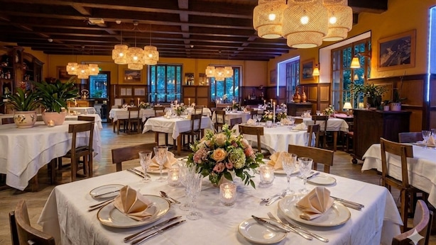 A restaurant with multiple tables set for dining, featuring chandeliers and floral centerpieces. - Hôtel Le Belvédère (Seez)