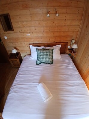 A wooden cabin room with a bed, two bedside tables, and a nightstand. - Hôtel Le Belvédère (Seez)