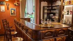 A bar area with wooden bar counter, bar stools, and a coffee machine. - Hôtel Le Belvédère (Seez)