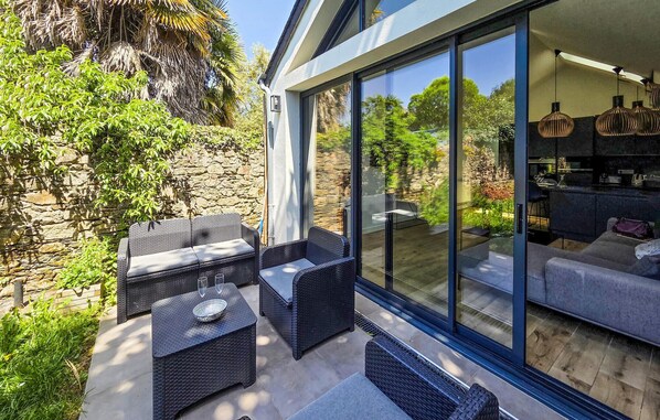 Eine moderne Außenpatio mit Korbmöbeln, einer Steinmauer und einem Wintergarten.