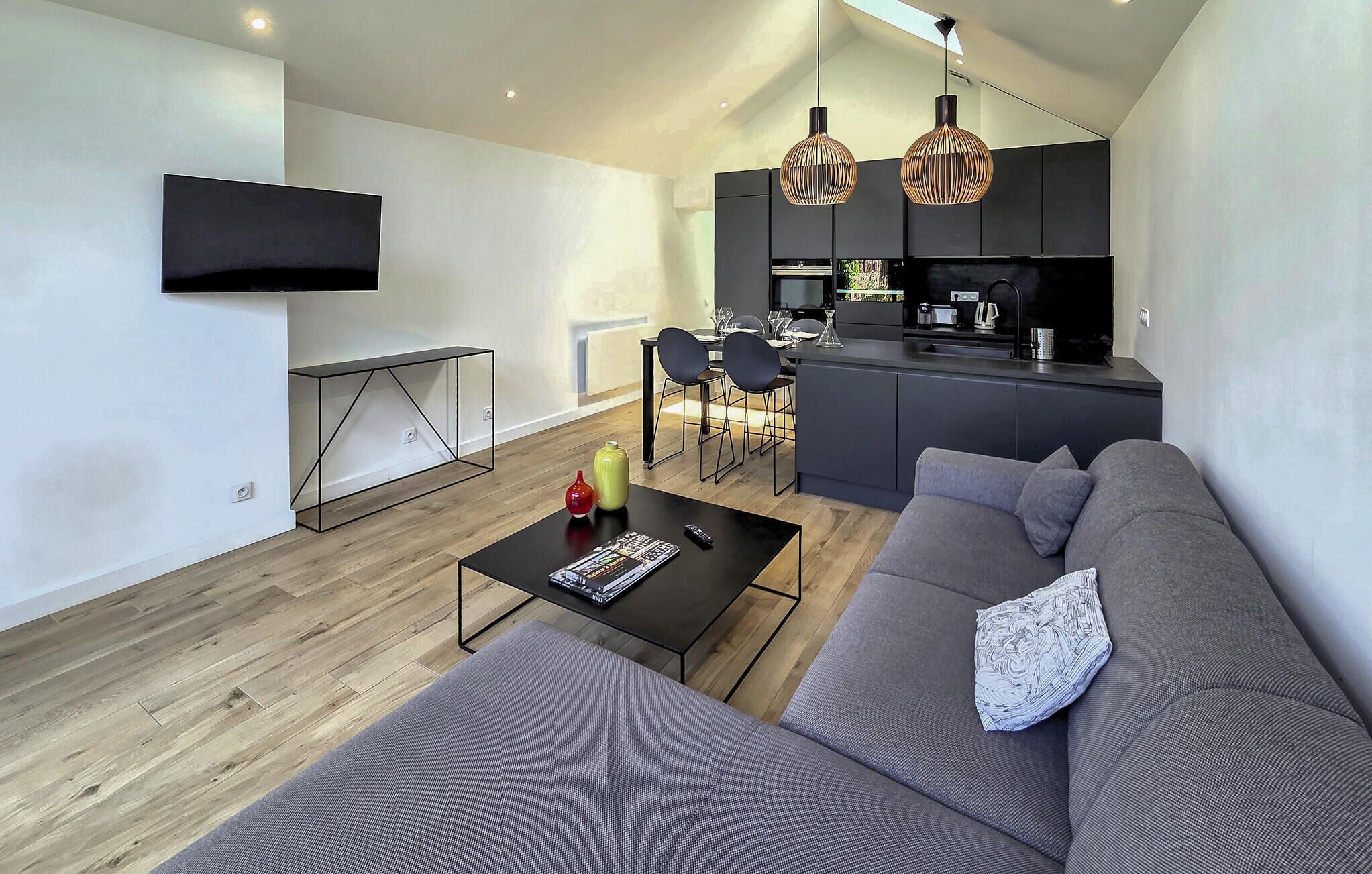 Un salon moderne avec un canapé, une table basse et un téléviseur fixé au mur.