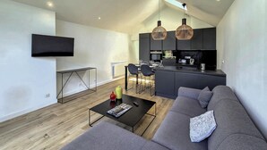 Un salon moderne avec un canapé, une table basse et un téléviseur fixé au mur.