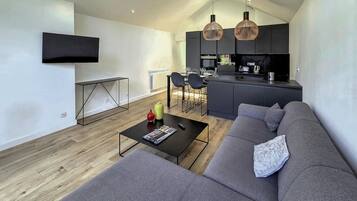 Un salon moderne avec un canapé, une table basse et un téléviseur fixé au mur.