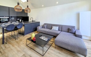 Ein modernes Wohnzimmer mit Sofa, Couchtisch und Essbereich.