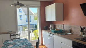 Una cocina con armarios blancos, encimera de madera y un comedor con mesa y sillas.