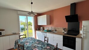 Una cocina con una mesa de comedor, sillas, armarios, un microondas, un fregadero y una estufa.