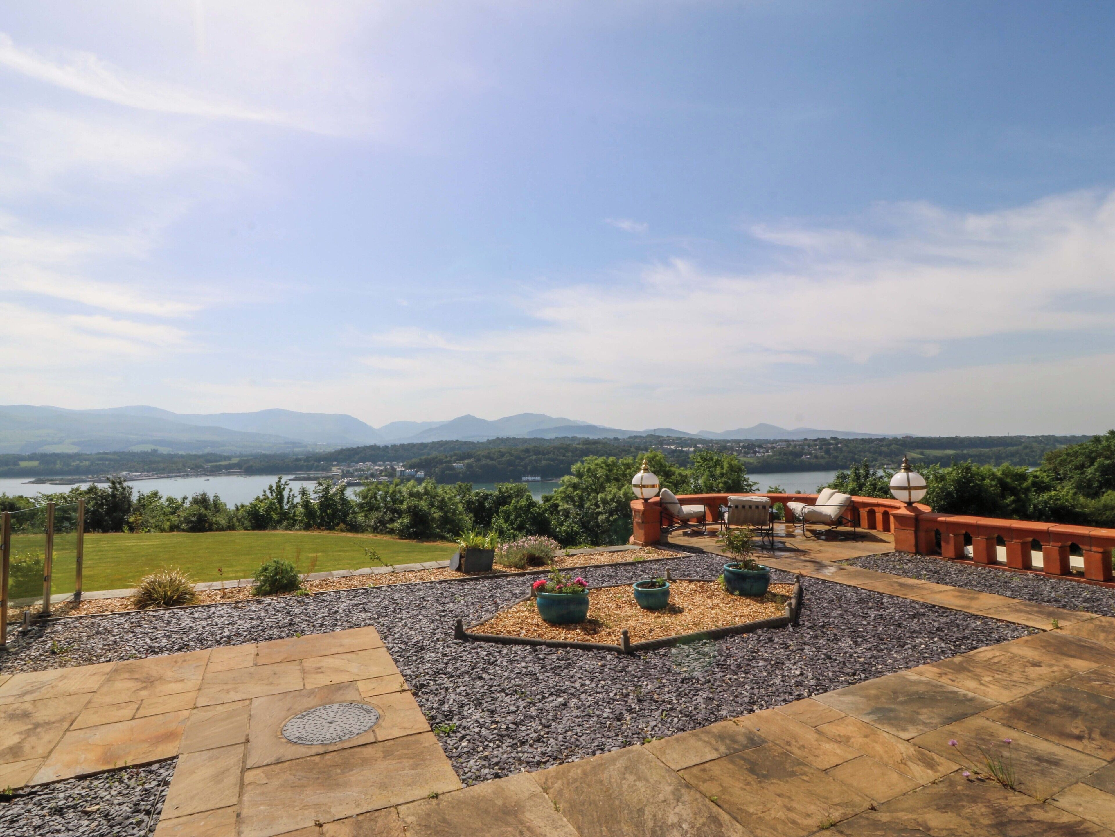 A patio with outdoor seating, a view of a lake, and distant mountains.
