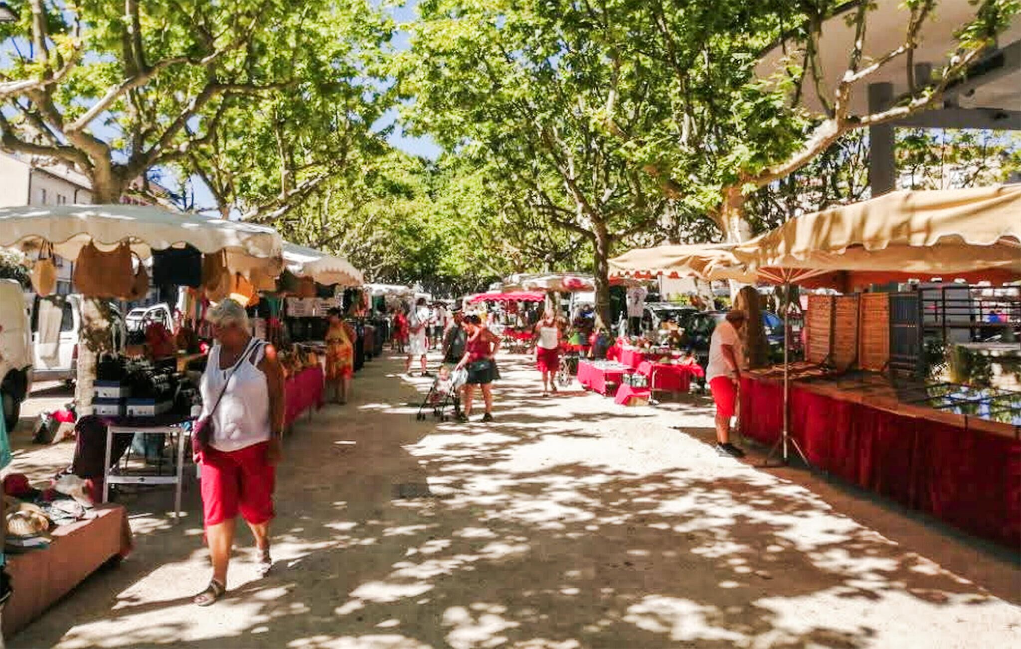 Un marché animé en plein air, avec de nombreux étals et beaucoup de monde.