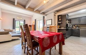 A dining area with a red tablecloth, wooden chairs, and a kitchen in the background. - Amazing home in Vers-Pont-Du-Gard with WiFi (Vers-Pont-Du-Gard)